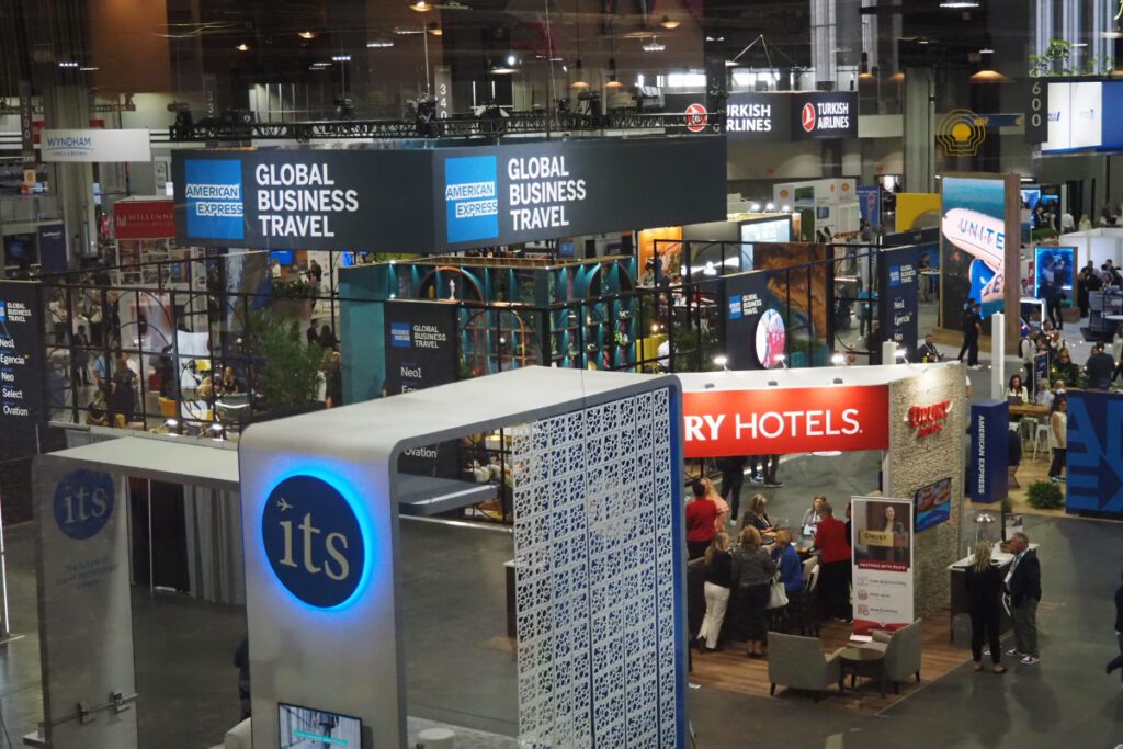 booths on the floor of a trade show that have the phrases business travel and hotels on signs