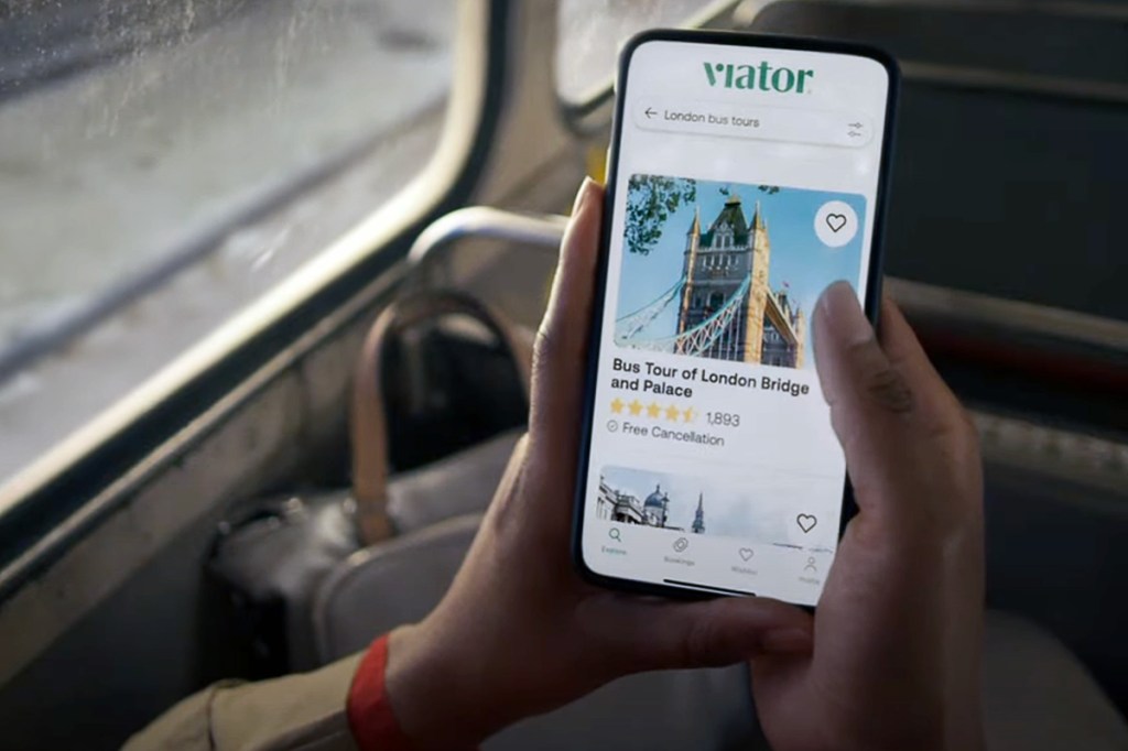 a person holding a smartphone while looking at a Viator website