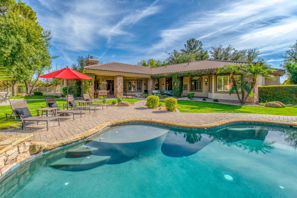 View of a large pool and ranch style house.