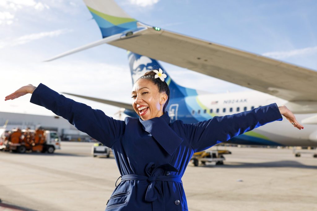 An Alaska Airlines flight attendant with an Alaska plane