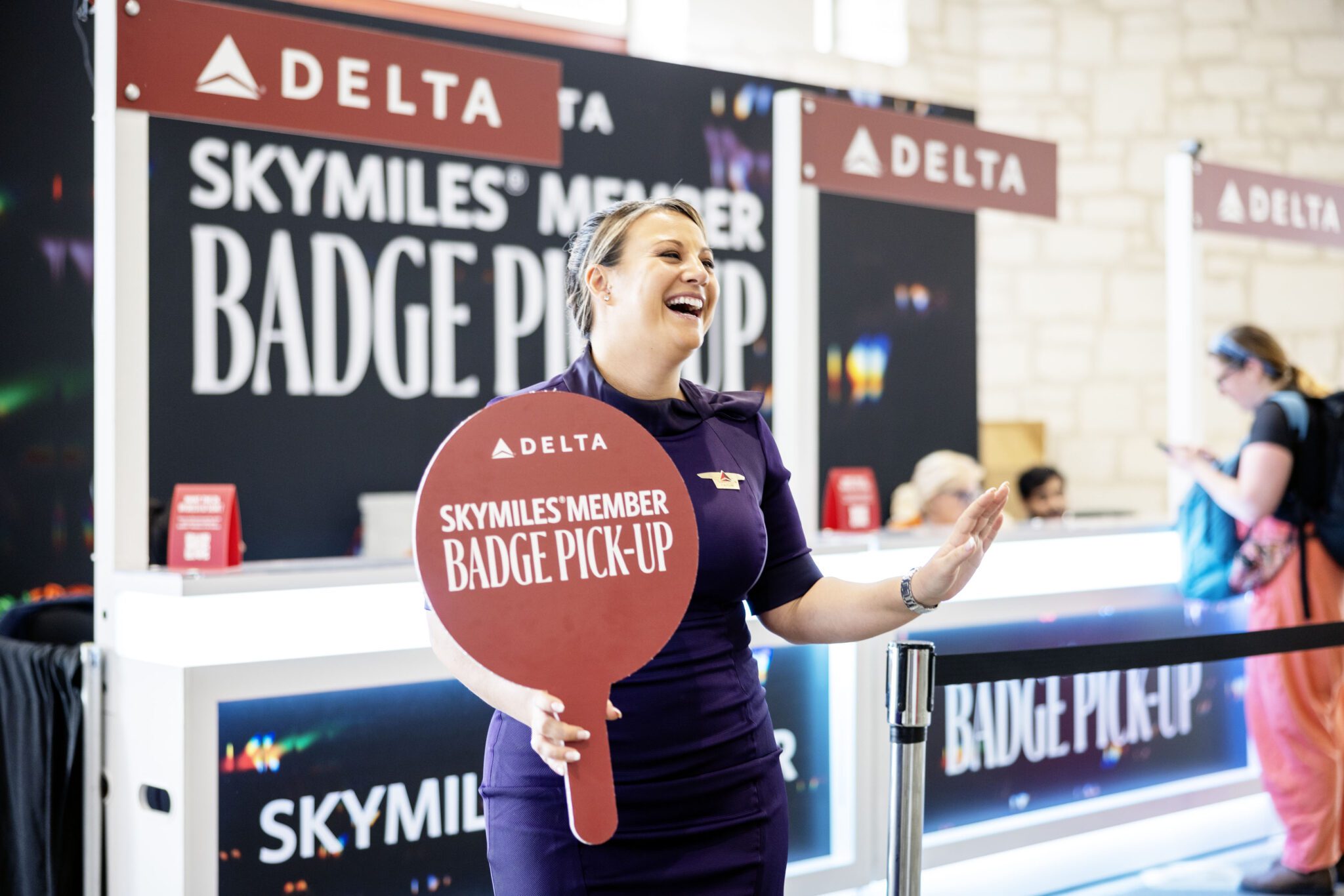 A Delta fight attendant assists guests at a badge pick-up area for SkyMiles Members during SXSW 2024.