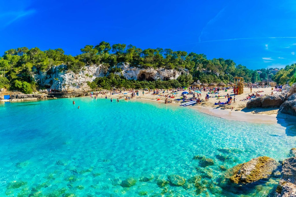 view of a turquoise sea and a beach filled with bathers