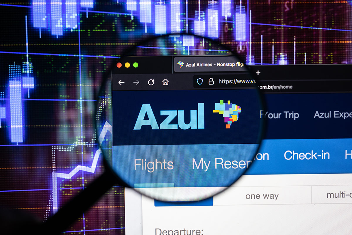 Azul airline company logo on a website with blurry stock market developments in the background, seen on a computer screen through a magnifying glass