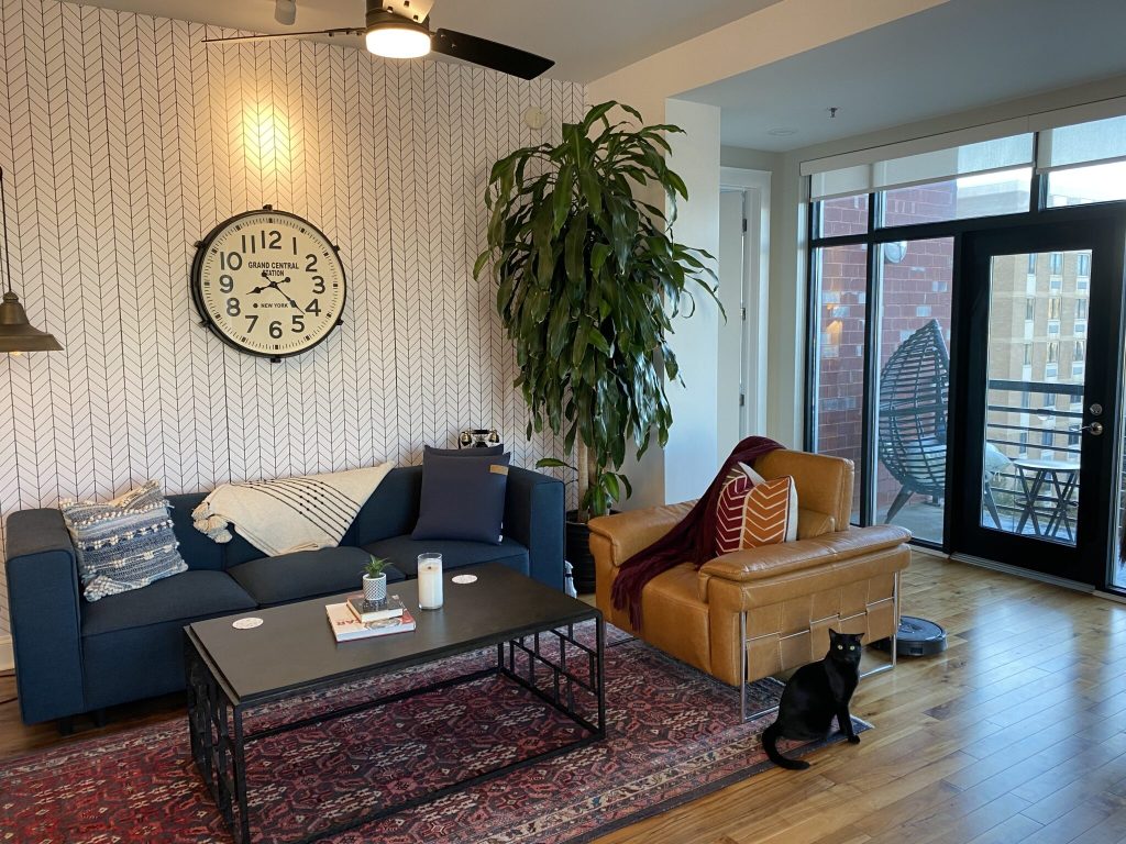 A living room with a sofa, coffee table, chairs and an outdoor view.