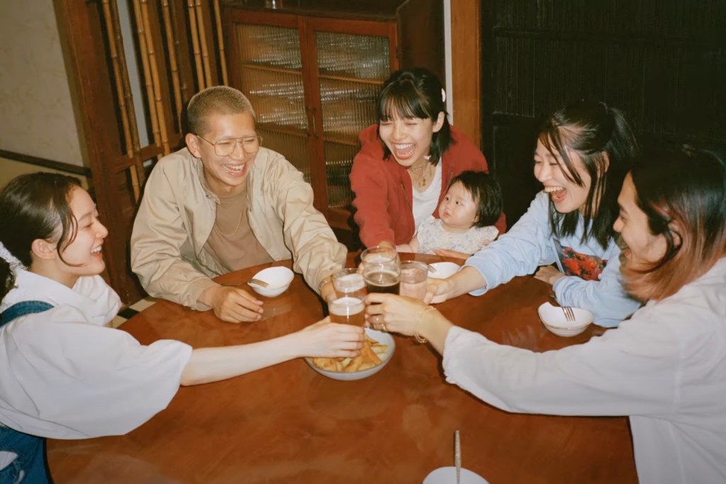 A Japanese family sitting around a table and laughing.