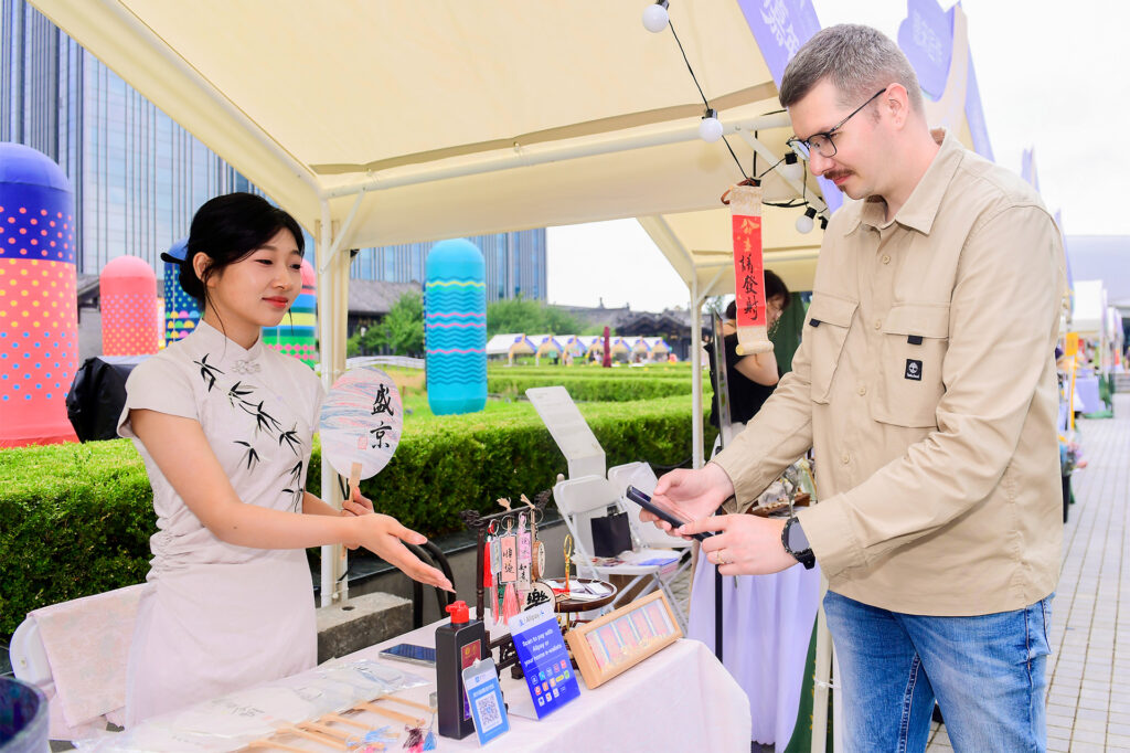 An international visitor paying with Alipay at a souvenir store in China e1729814185216