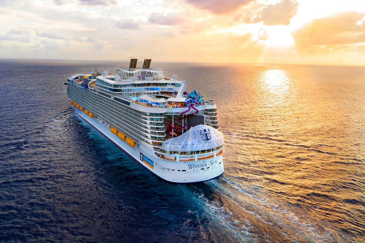 An aerial view of the Wonder of the Seas cruise ship on the ocean at sunset.