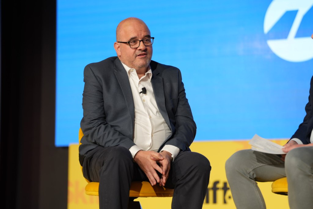 A man sitting on a yellow chair at a conference