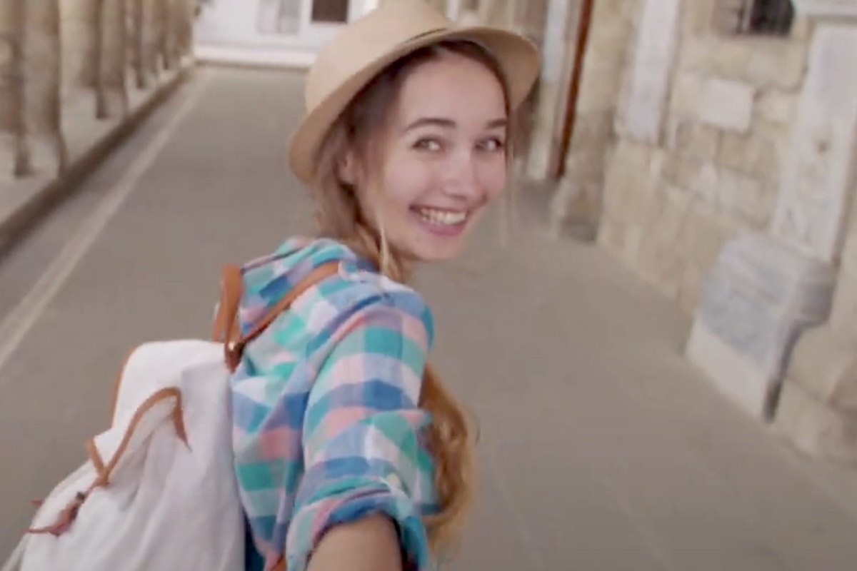 A woman travel in a hat with a backpack.