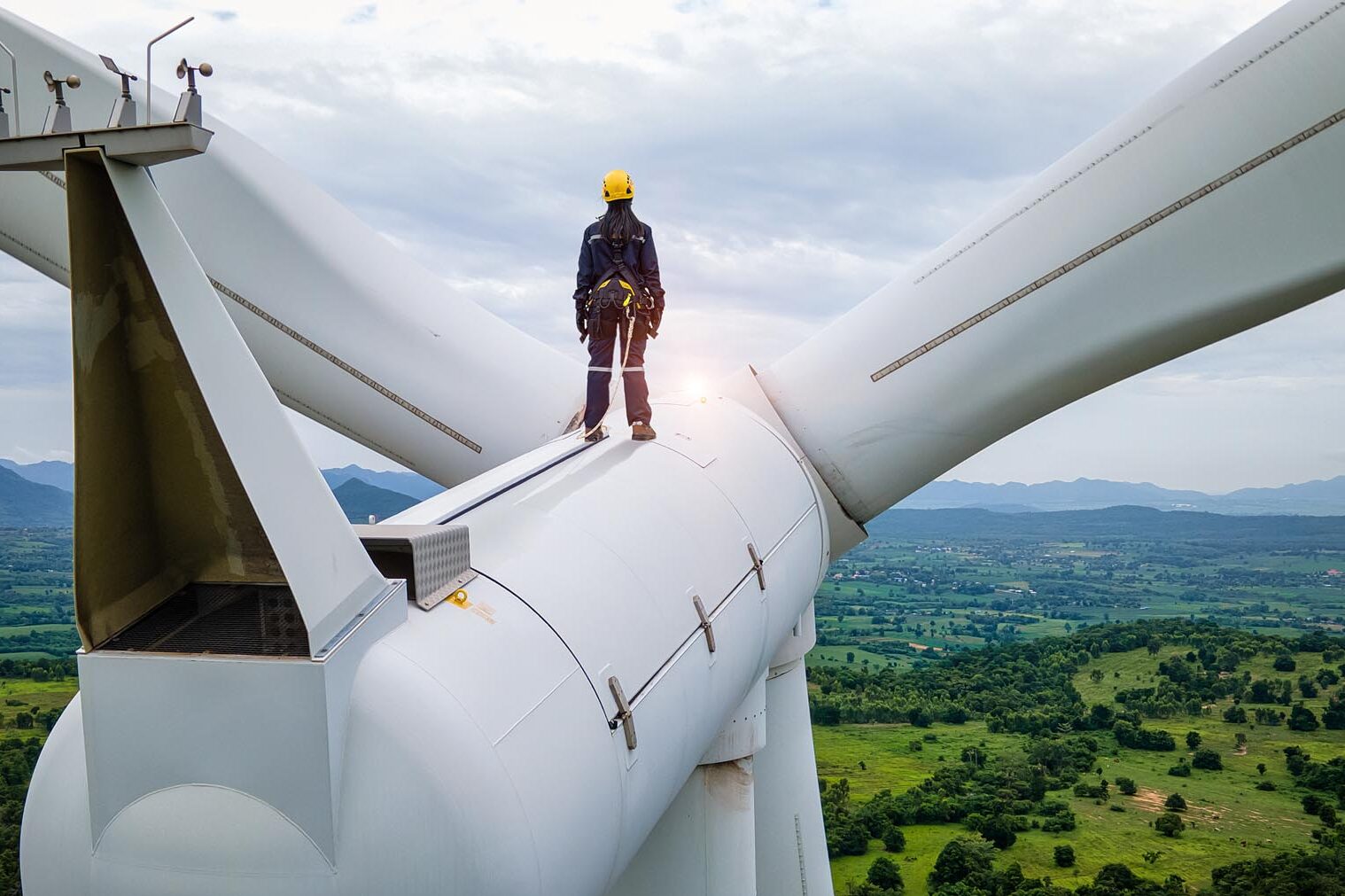 An engineer standing on top of a wind turbine and looking beautiful landscape.