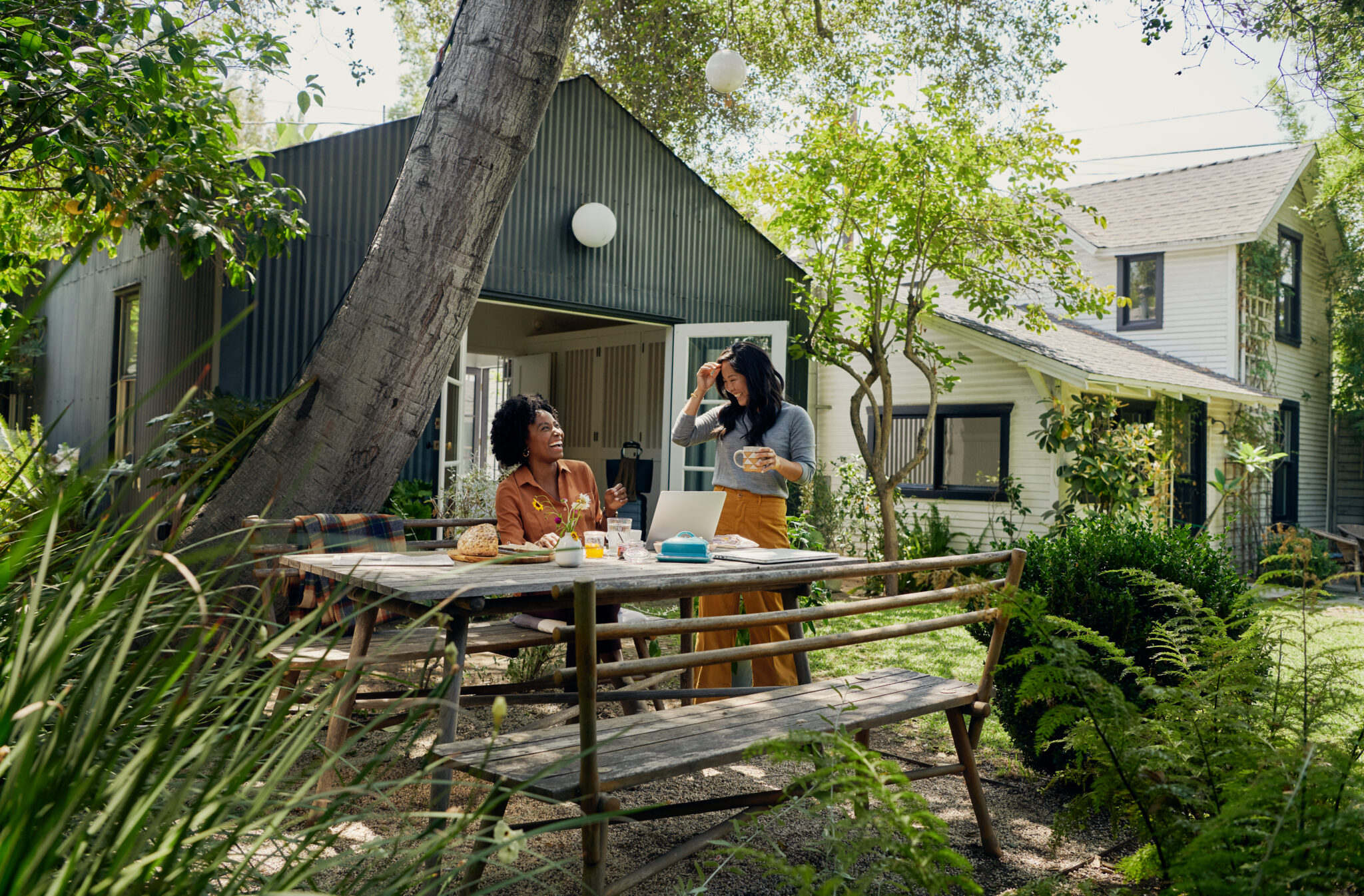 Two women sitting at a table outside an Airbnb.