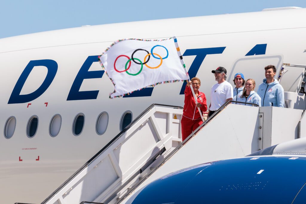 The mayor of Los Angeles steps off a Delta aircraft with the Olympic flag.