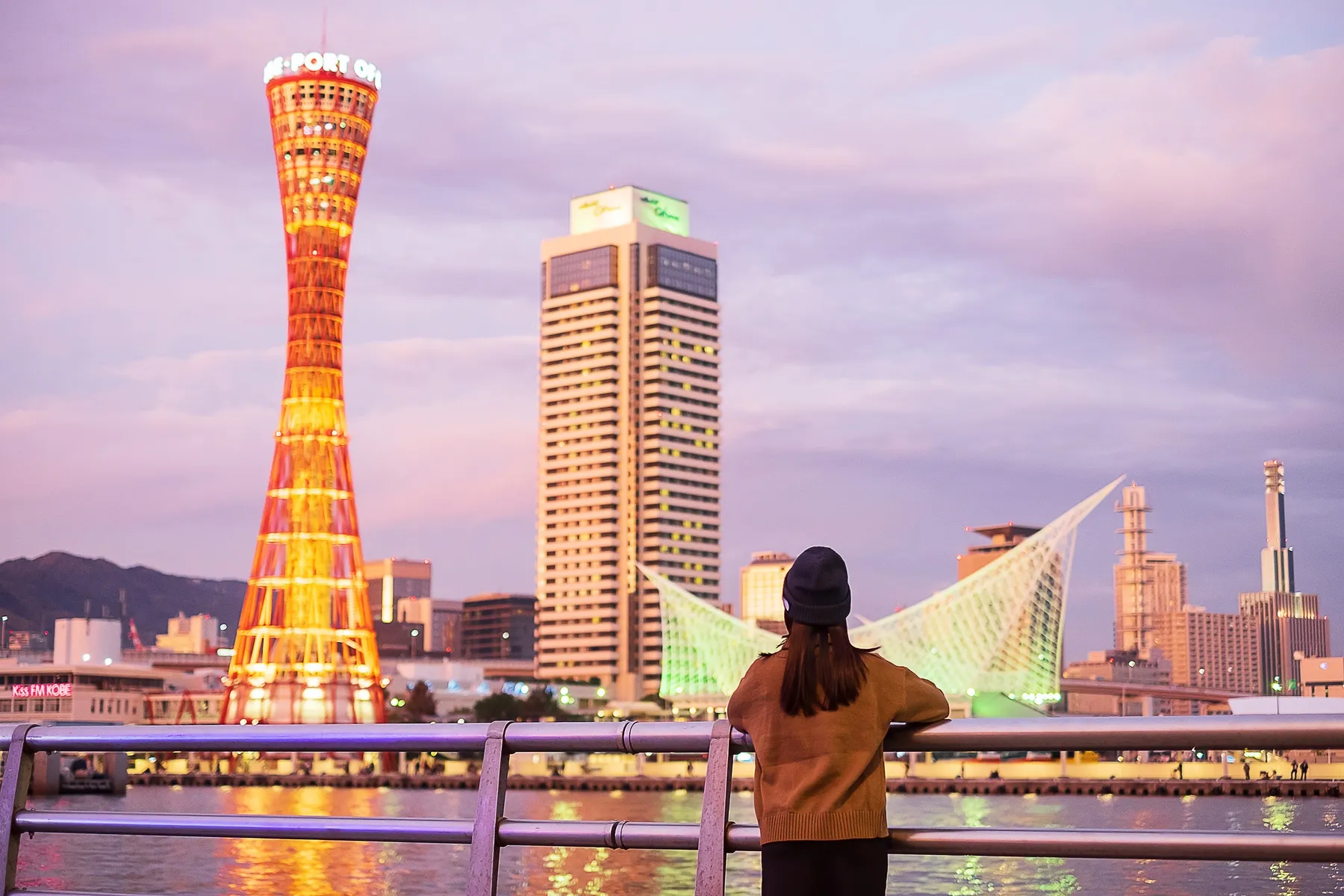 A woman overlooking water in front of a city skyline.