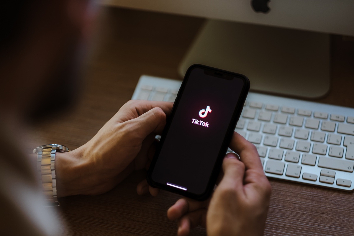 A man holding an iPhone with TikTok app logo on the screen.