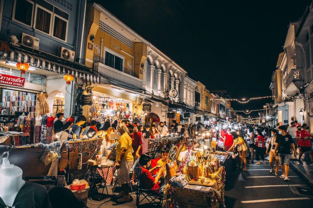 Shoppers and sellers in a a lively night market in Southeast Asia.