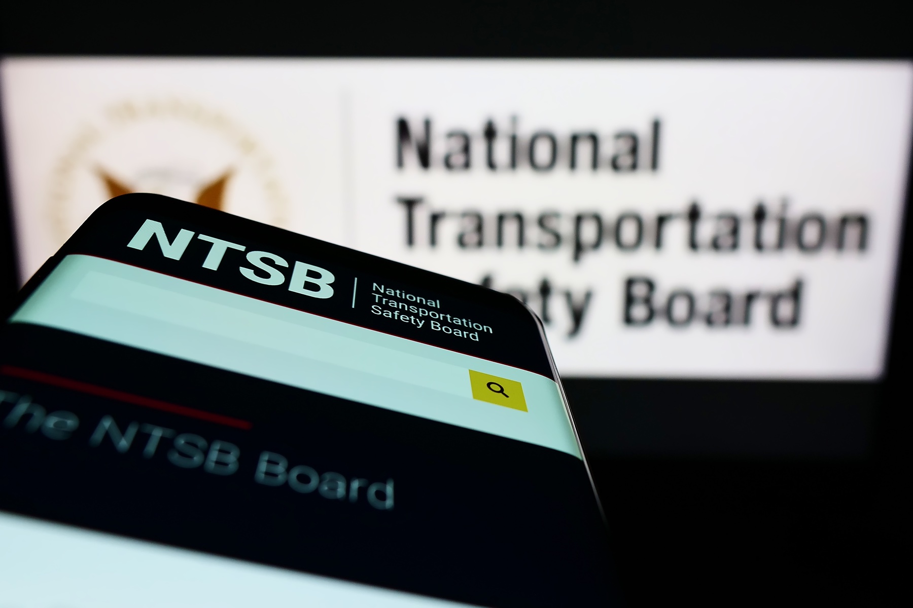 A smartphone and computer screens with the logo of the NTSB agency