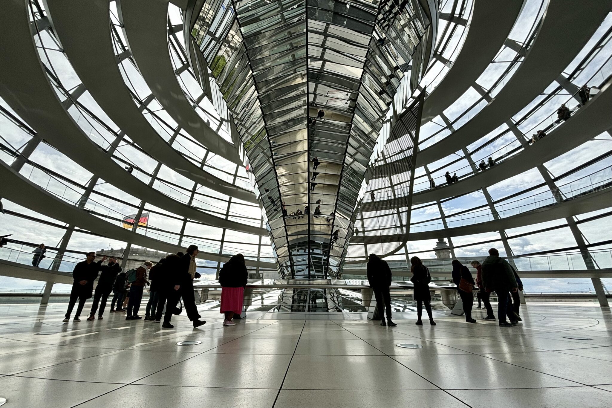 People gather around placards in a domed and light filled reflective room.