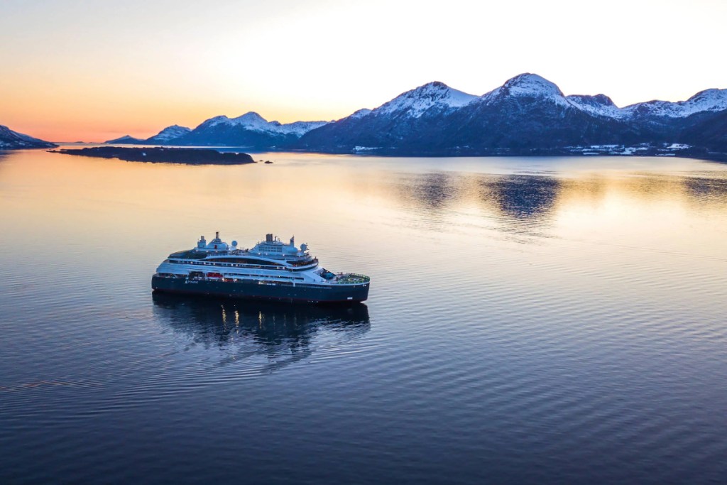 a small yacht-style boat on a fjord at dusk