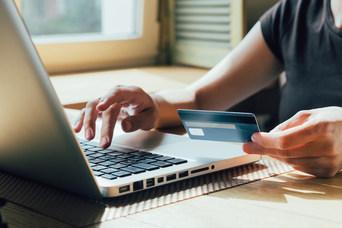 view of hands typing and holding a credit card