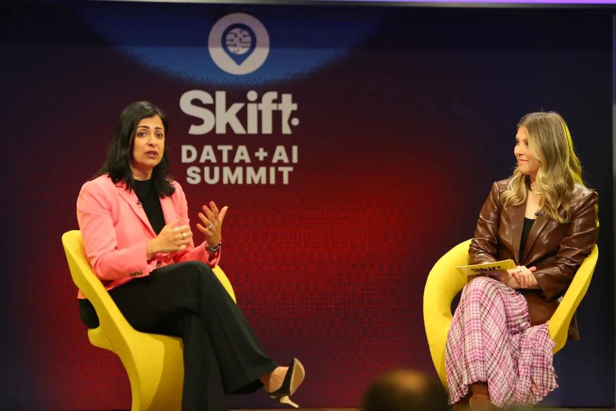 Two women sitting on a stage talking at a conference.