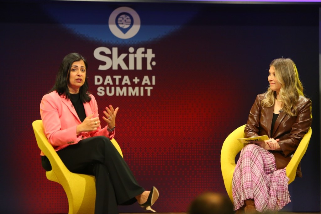 Two women sitting on a stage talking at a conference.